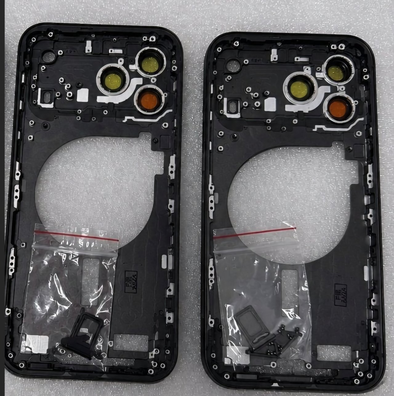 Deux cadres arrière de smartphone noir identiques, avec trois découpes circulaires pour objectifs, posés côte à côte sur de la mousse