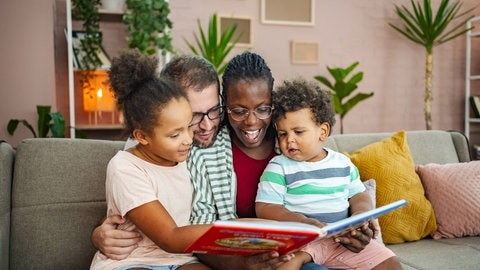 Une famille lit ensemble un livre dans le salon.