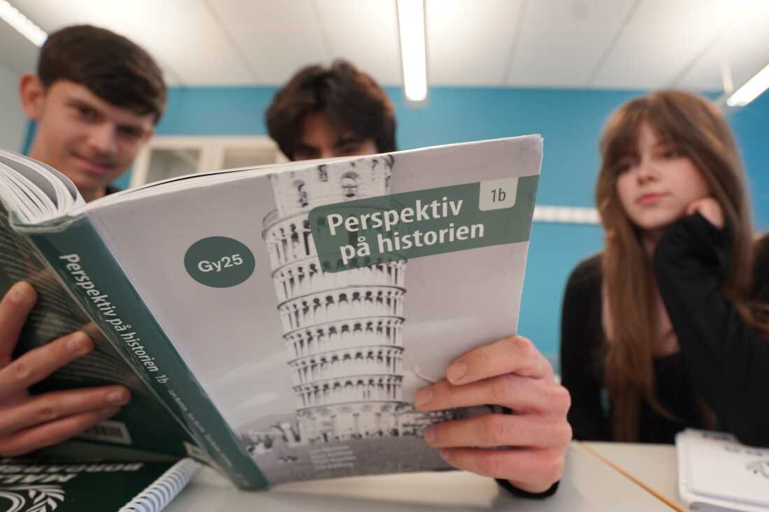 Des élèves de lycée posent avec un manuel d'histoire à l'école Malmo Borgarskola, Malmö, Suède, le 21 mai 2026.