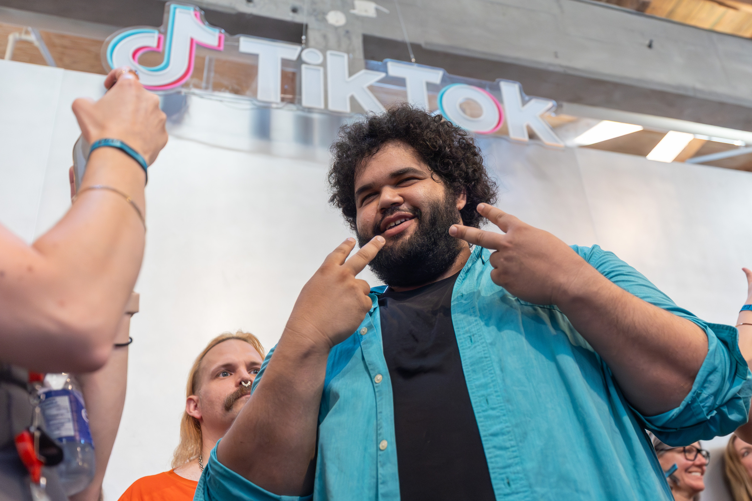 Mounir Kaddouri sourit et fait des signes de paix sous un logo TikTok.